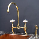 Unlacquered brass curved legs bridge faucet – high-arc spout detail