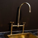 Polished brass bridge faucet – installed in traditional kitchen with farmhouse sink