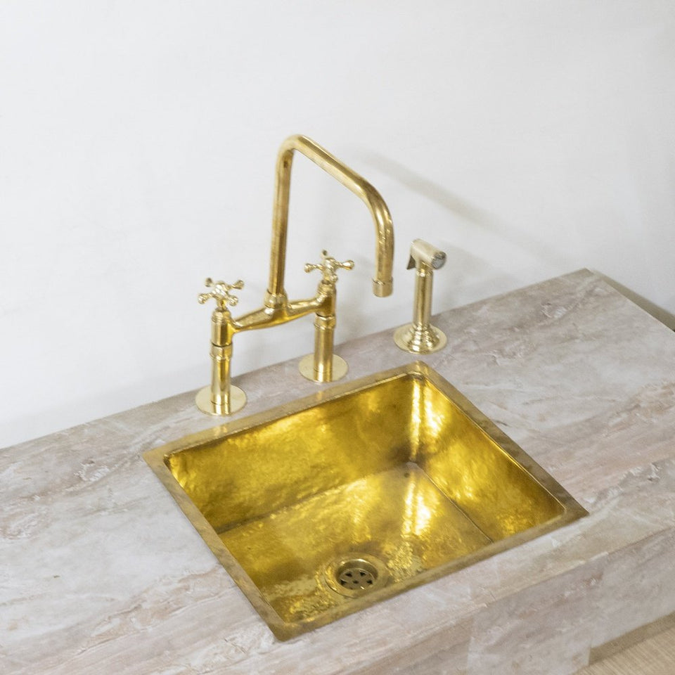 Unlacquered brass bridge kitchen faucet with hand sprayer – front view