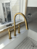 Unlacquered brass bridge faucet with pull-down spray and lever handles – front view