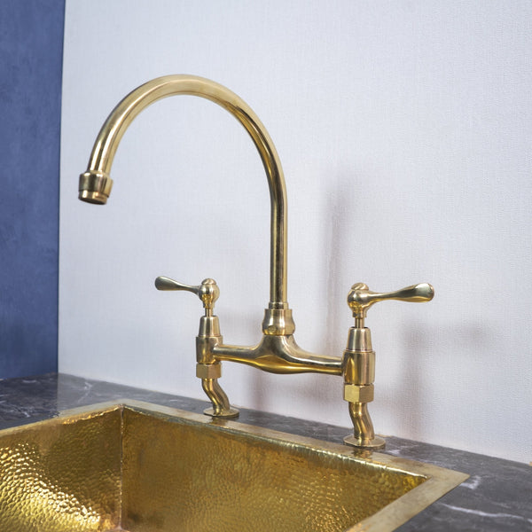 Unlacquered brass curved legs bridge kitchen faucet – front view, natural patina